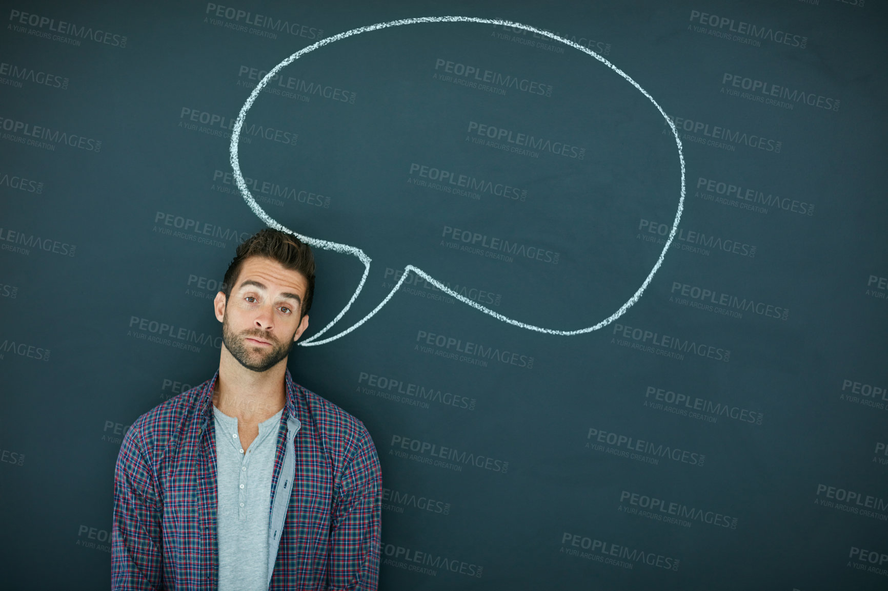 Buy stock photo Portrait of a young man standing in front of a blackboard with a speech bubble drawn on it