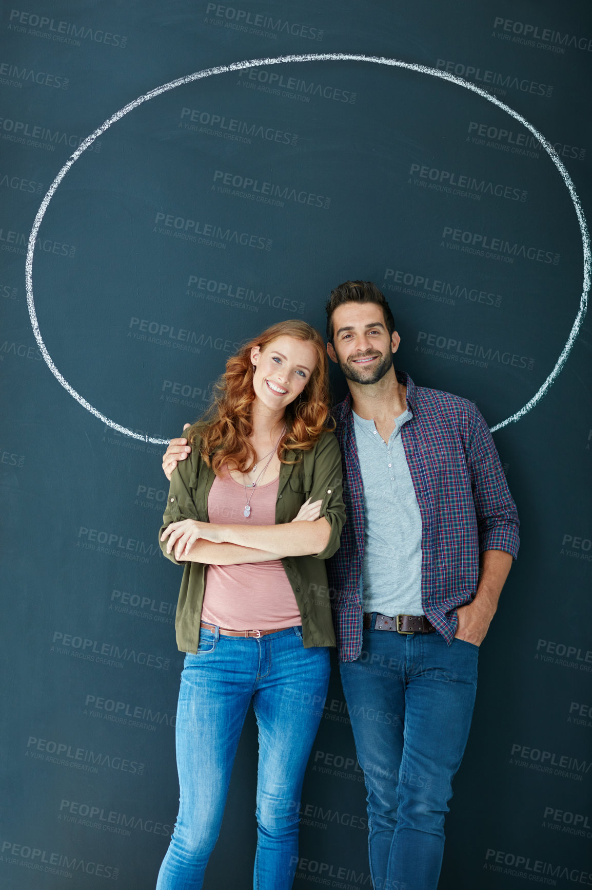 Buy stock photo Portrait of a young couple standing in front of a blackboard with a circle drawn around them