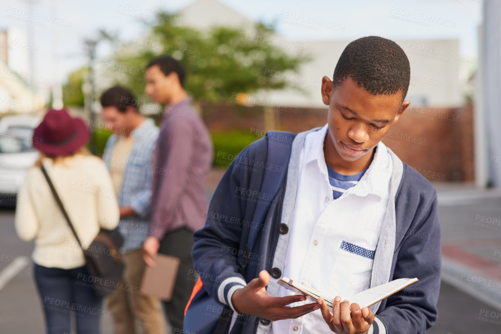 Buy stock photo Cropped shot of a university student reading his notebook on campus