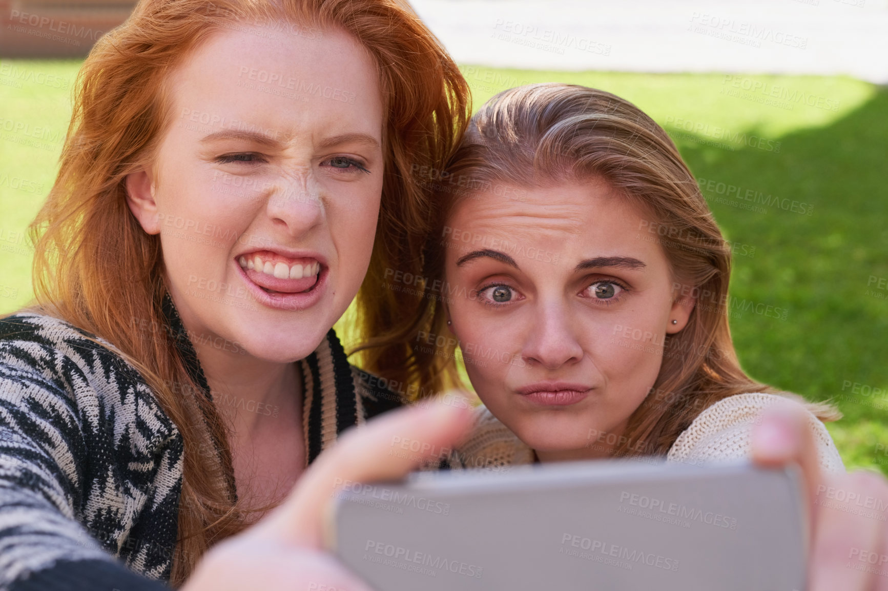 Buy stock photo Shot of two young friends taking a selfie together with a phone