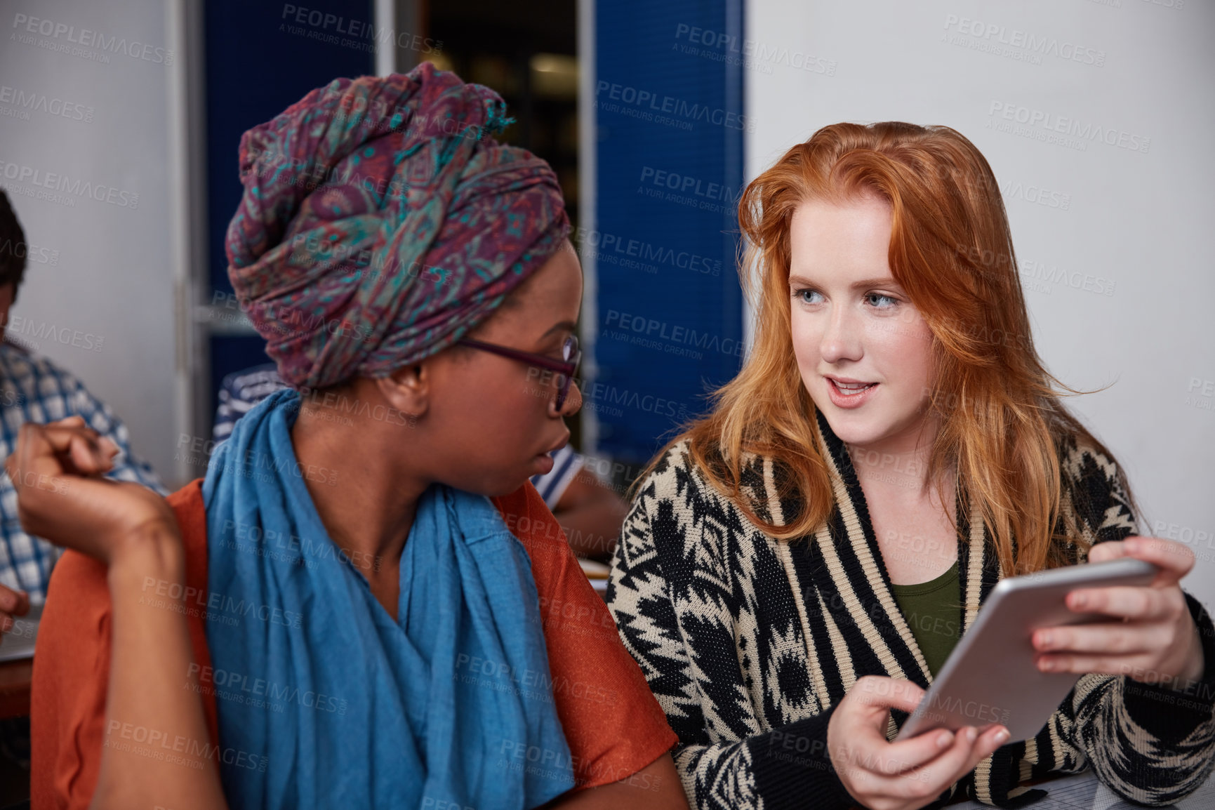 Buy stock photo Cropped shot of two university students having a discussion on a digital tablet in class