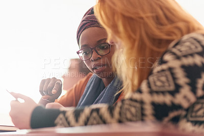 Buy stock photo Cropped shot of two university students having a discussion in class