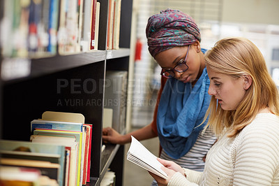 Buy stock photo Cropped shot of two university students working together in the campus library