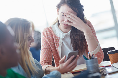 Buy stock photo Shot of a worried looking university student showing a text message to her friend