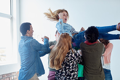 Buy stock photo Shot of a group of university students tossing another student in their air during class