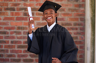 Buy stock photo Portrait of a happy male student standing with his diploma on graduation day
