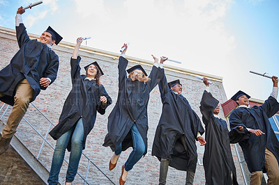 Buy stock photo Low angle shot of a happy group of students jumping in celebration on graduation day
