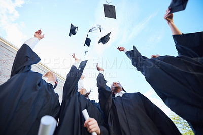 Buy stock photo Low angle shot of a group of students throwing their caps into the air on graduation day