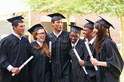 Buy stock photo Shot of a happy group of students standing outside on their graduation day