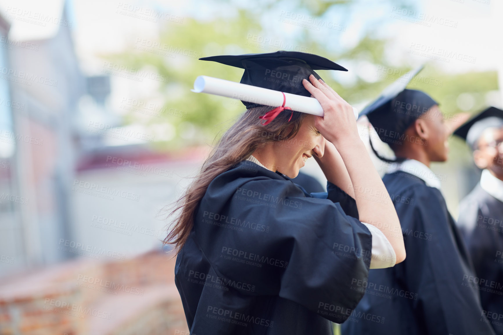 Buy stock photo Shot of a happy group of students standing outside on their graduation day