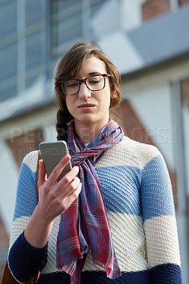 Buy stock photo Cropped shot of a university student texting on her cellphone on campus