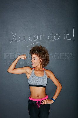 Buy stock photo Shot of a woman flexing her muscles against a chalk background with a motivational message