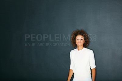 Buy stock photo Studio shot of a serious young woman posing against a dark background