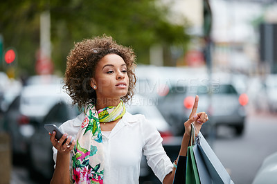 Buy stock photo Shot of an attractive young woman hailing a cab while on a shopping spree in the city
