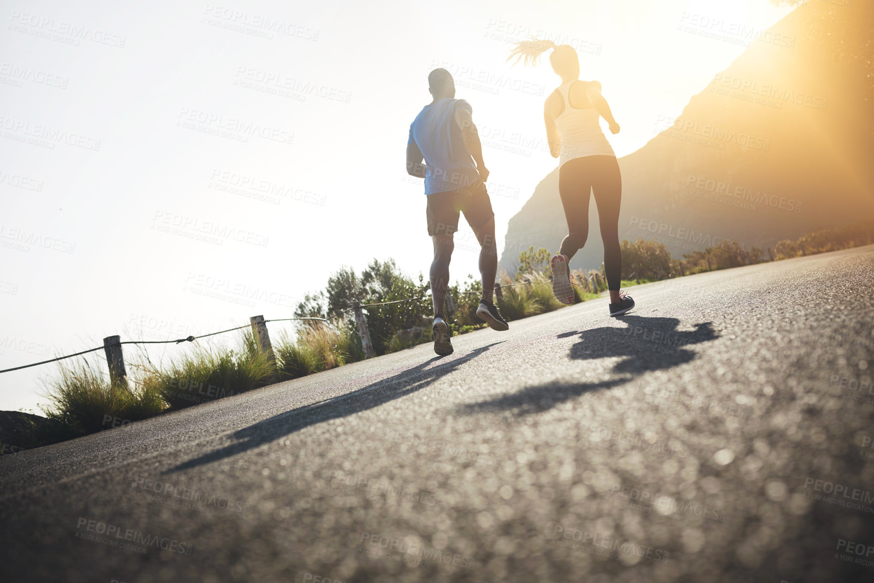 Buy stock photo Low angle shot of two people running on a tarmac road