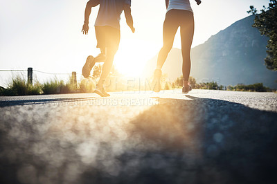 Buy stock photo Cropped shot of two unrecognizable people running on a tarmac road