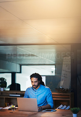 Buy stock photo Cropped shot of a young designer working late on a laptop in an office
