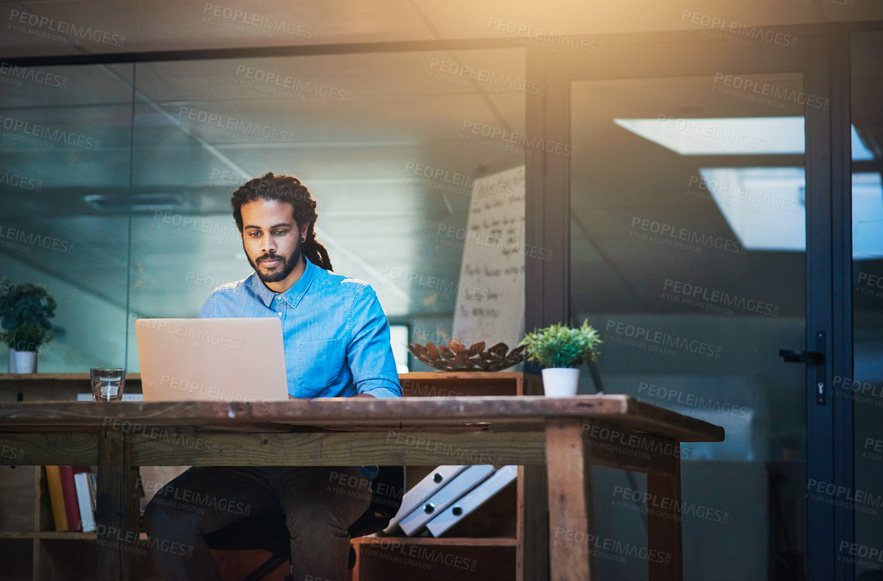 Buy stock photo Cropped shot of a young designer working late on a laptop in an office