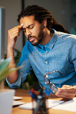 Buy stock photo Cropped shot of a young designer looking stressed out while working late in an office