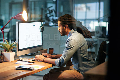 Buy stock photo Cropped shot of a young designer working late on a computer in an office