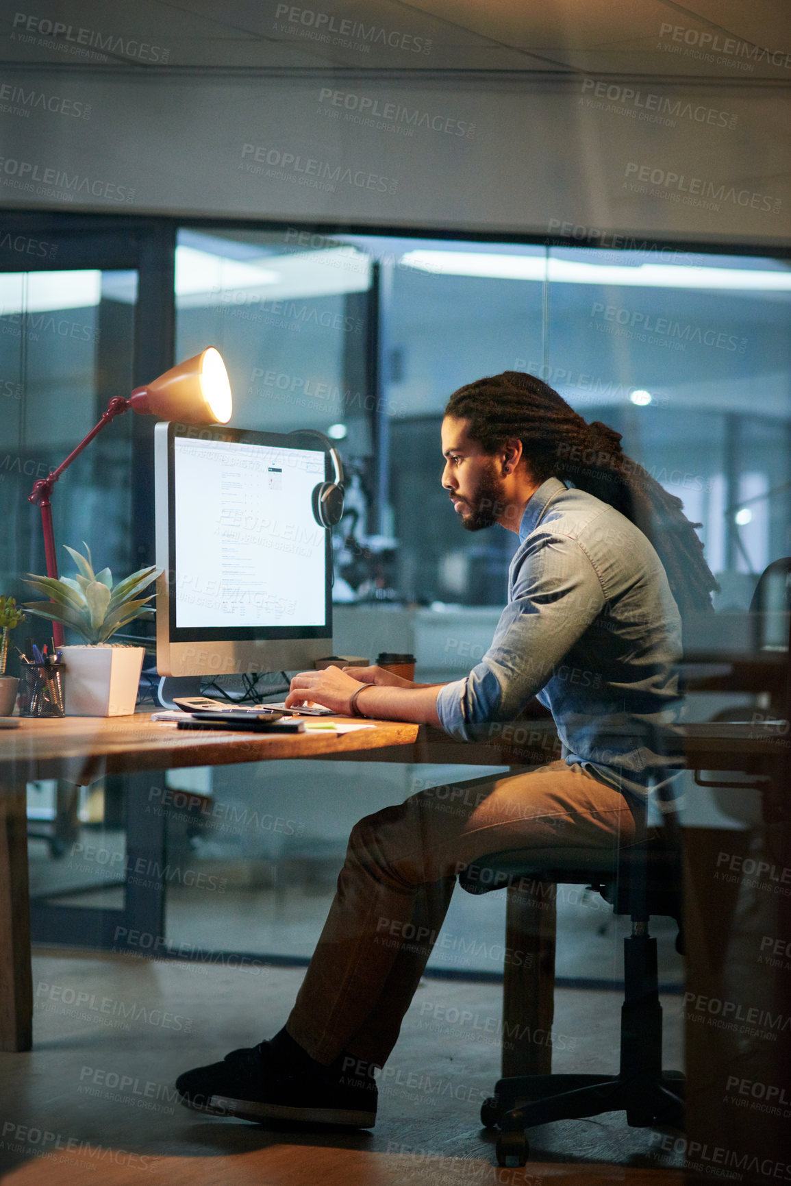 Buy stock photo Shot of a young designer working late on a computer in an office