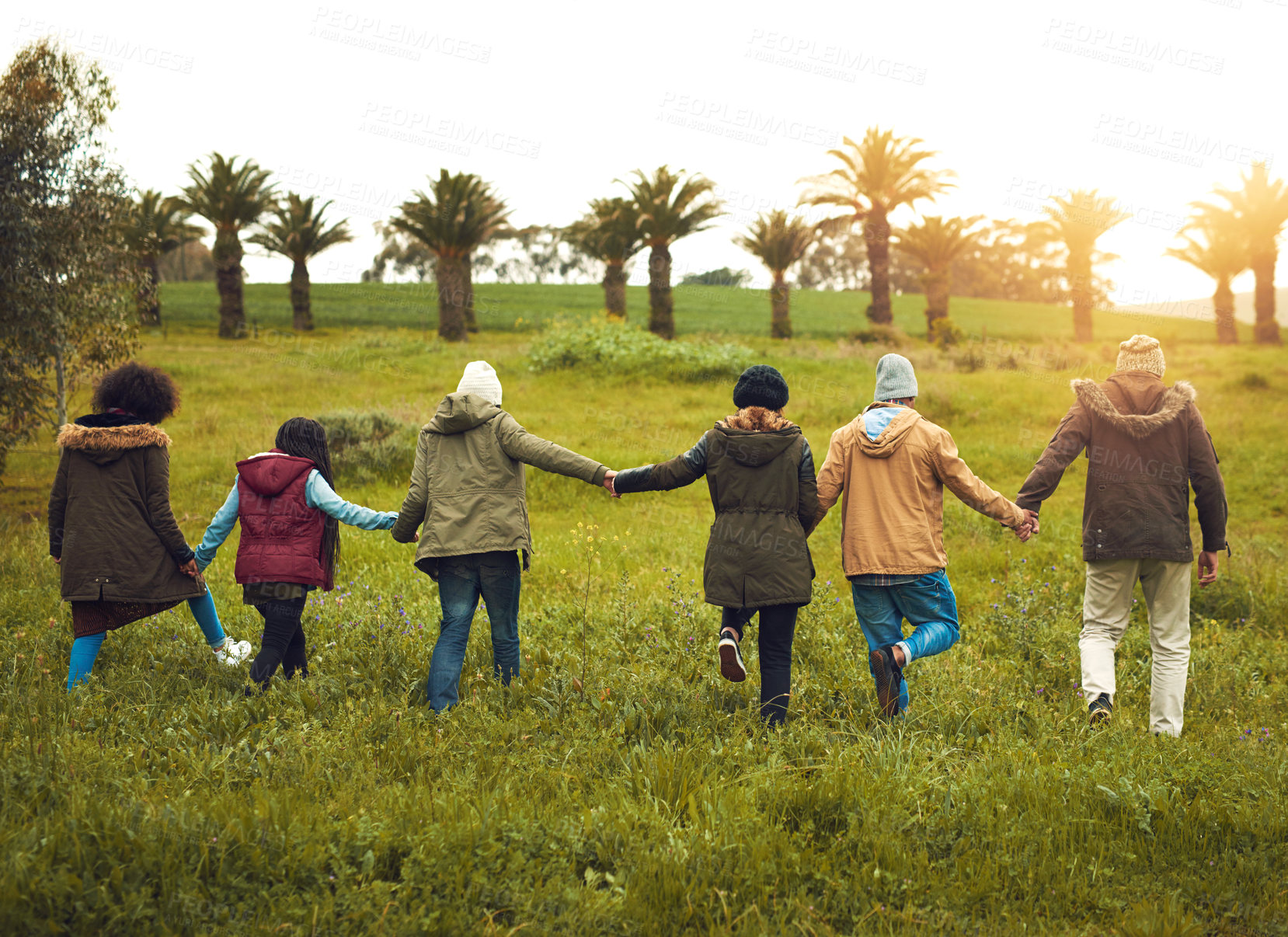Buy stock photo Rearview shot of a group of friends walking through a field together