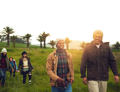 Buy stock photo Shot of a group of friends walking through a field together