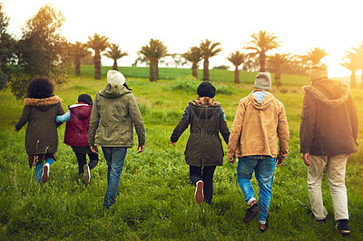 Buy stock photo Rearview shot of a group of friends walking through a field together