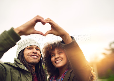 Buy stock photo Shot of two friends making a heart shape with their hands while standing outside