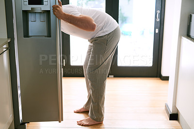 Buy stock photo Shot of a man peering into the fridge at home