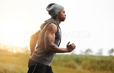 Buy stock photo Shot of a healthy young man out for a run in nature
