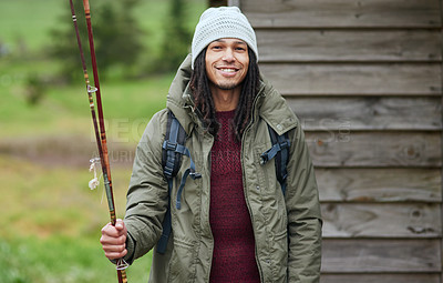 Buy stock photo Portrait of a happy young man standing outside with his fishing rod in his hand