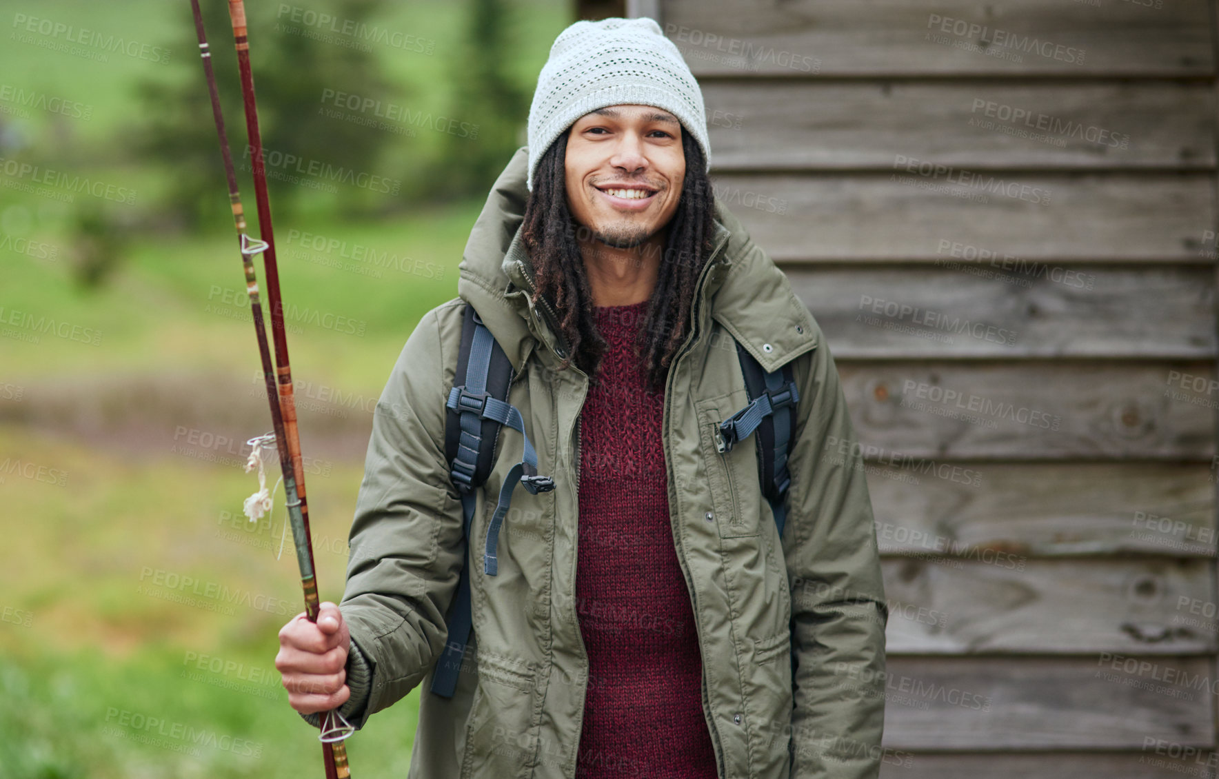 Buy stock photo Portrait of a happy young man standing outside with his fishing rod in his hand