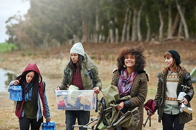 Buy stock photo Shot of a group of friends working together to carry supplies to their campsite