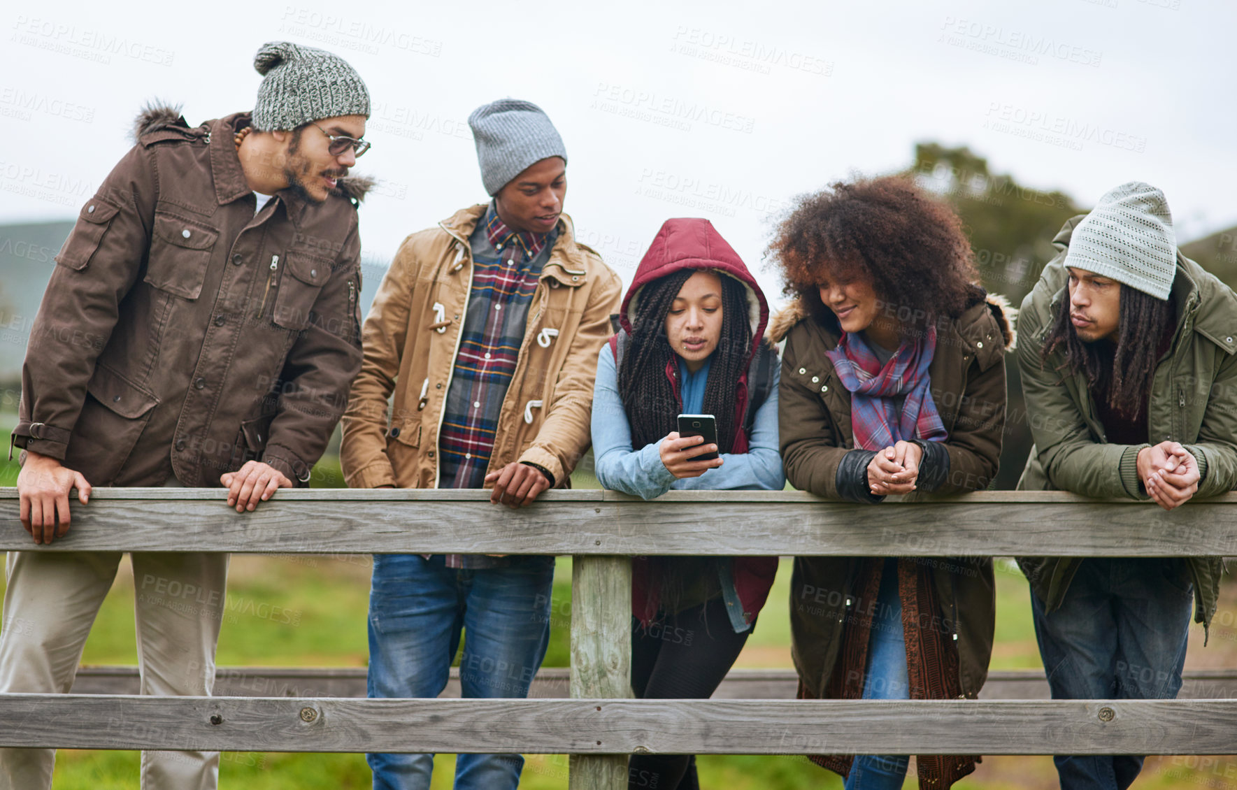 Buy stock photo Shot of a group of friends hanging out on a wooden bridge together