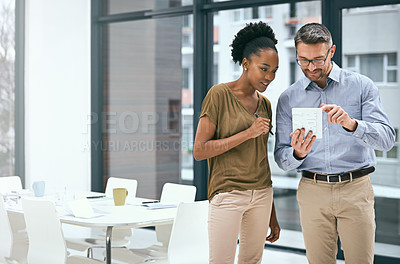 Buy stock photo Cropped shot of two colleagues working together on a digital tablet in an office