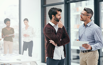 Buy stock photo Shot of two colleagues working together on a digital tablet in an office