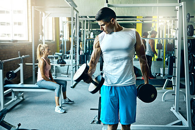 Buy stock photo Shot of a young man working out alone in the gym