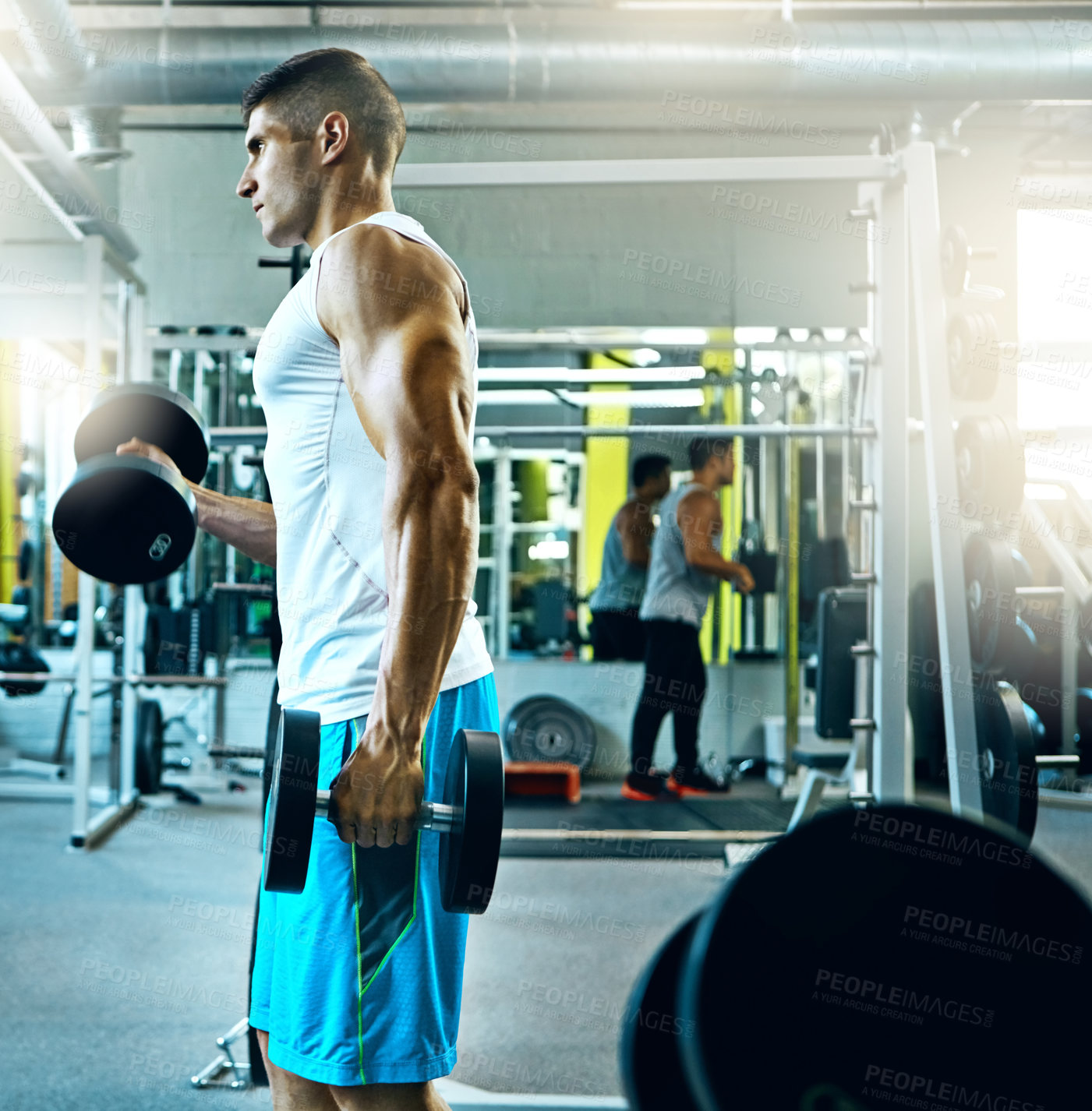 Buy stock photo Shot of a young man working out alone in the gym