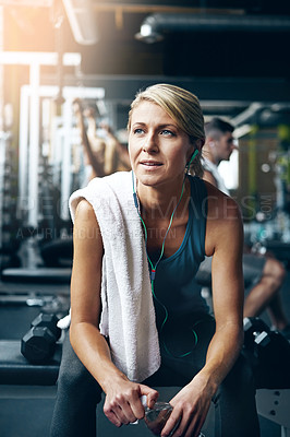 Buy stock photo Shot of a sporty woman taking a break between workouts