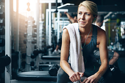 Buy stock photo Shot of a sporty woman taking a break between workouts