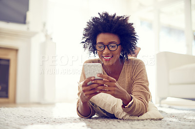 Buy stock photo Shot of a young woman using her phone at home
