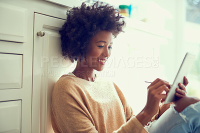Buy stock photo Shot of a young woman using a digital tablet at home