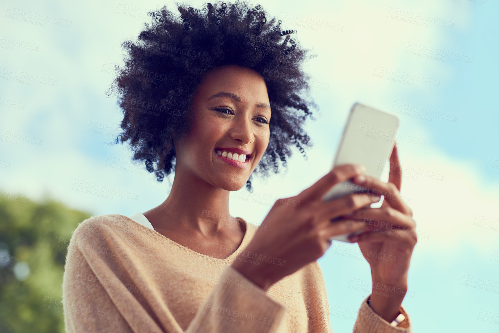 Buy stock photo Shot of a young woman using her phone outside