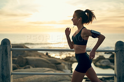 Buy stock photo Shot of a sporty young woman running along the esplanade