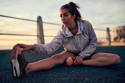 Buy stock photo Shot of a sporty young woman stretching before her run