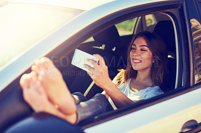 Buy stock photo Shot of a young woman taking a selfie while sitting in her car
