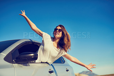 Buy stock photo Shot of a young woman leaning out of her car window with her arms outstretched