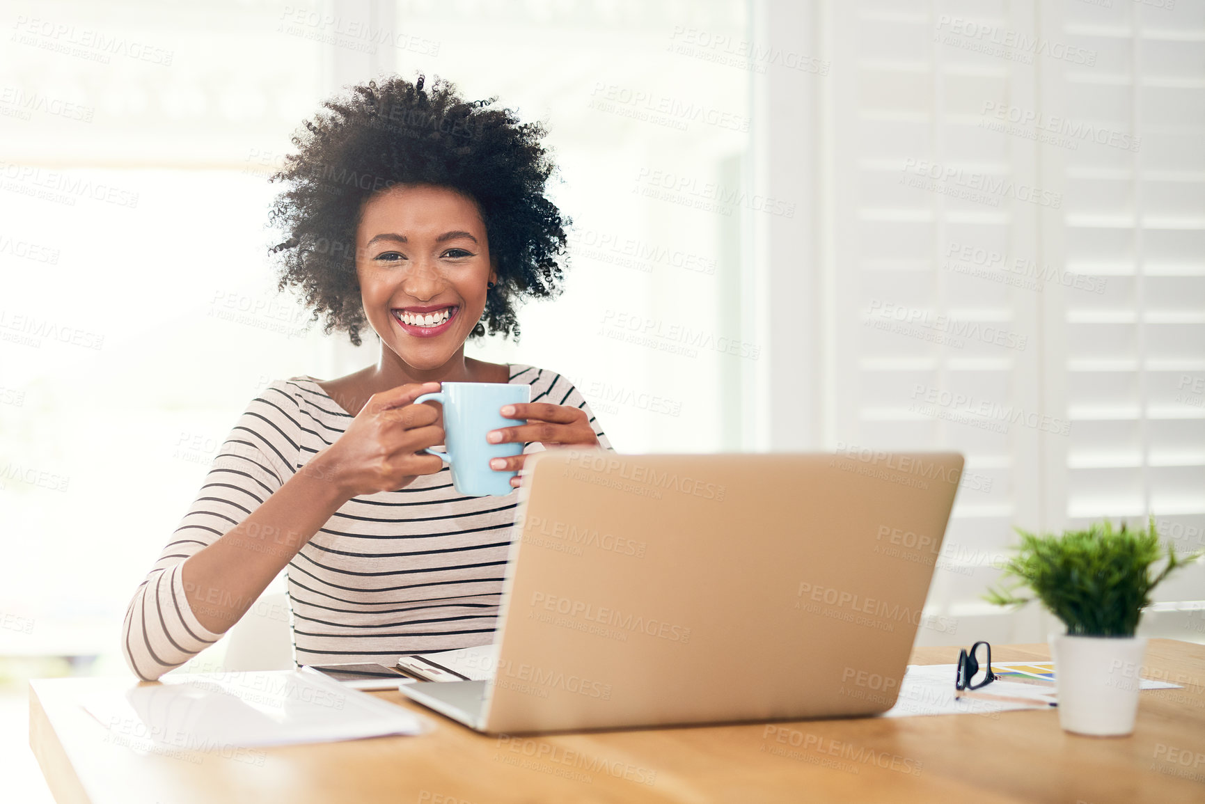 Buy stock photo Portrait of a young woman drinking coffee while working on her laptop at home