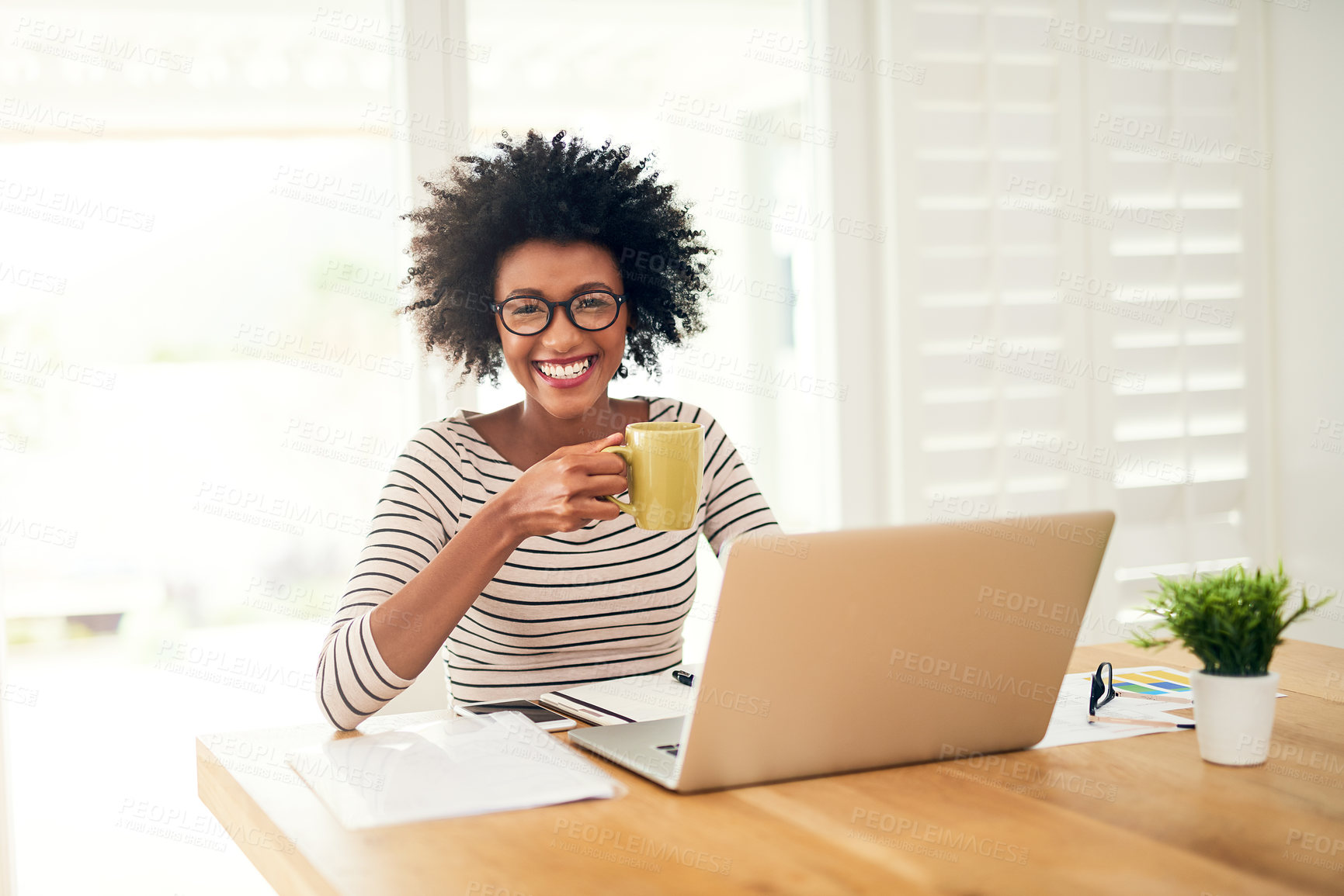 Buy stock photo Portrait of a young woman drinking coffee while working on her laptop at home